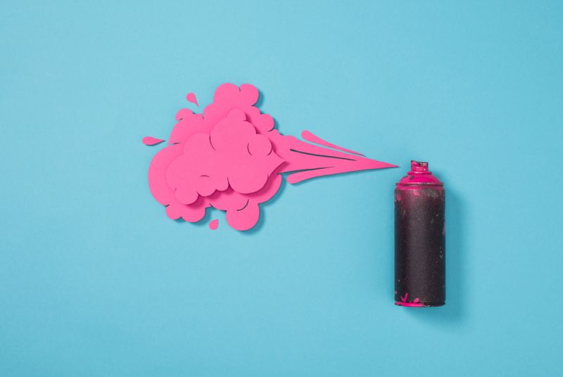 top view of spray paint in can and paper splashes isolated on blue